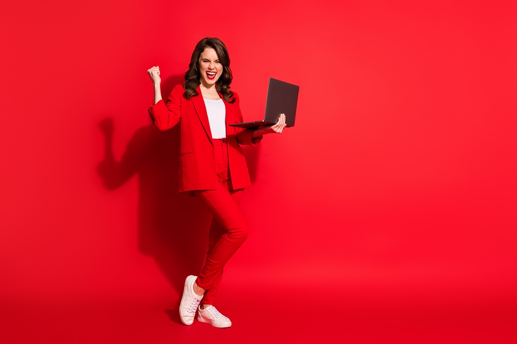 Texas Defensive Driving full length photo of pretty young girl hold netbook raise arm stand tiptoe wear jacket pants footwear isolated red color background